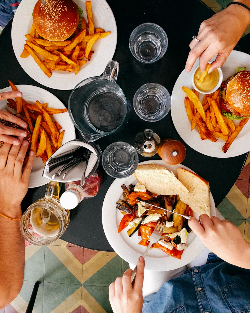 Des amis partagent des burgers et des frites autour d’une table