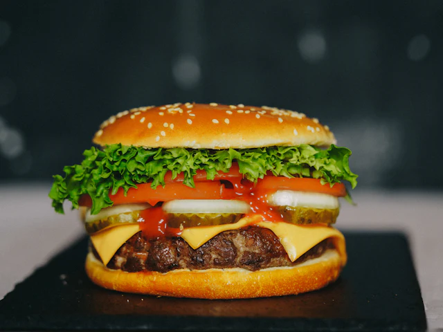 Un cheeseburger avec laitue, tomate et cornichons