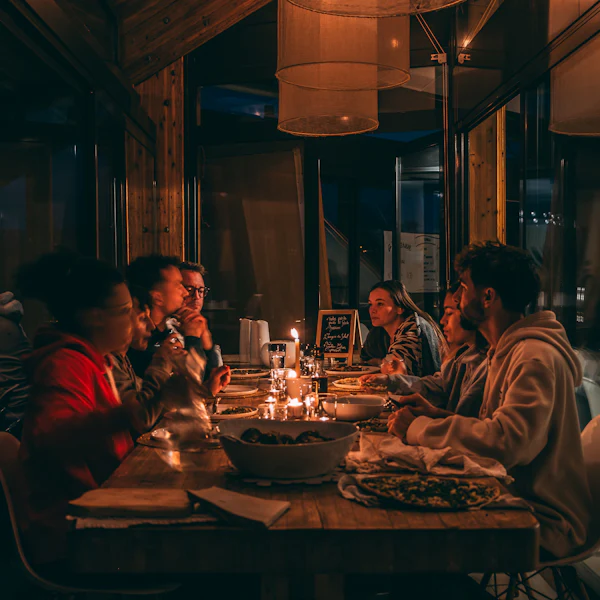 Des convives partagent un dîner dans une salle chaleureusement éclairée