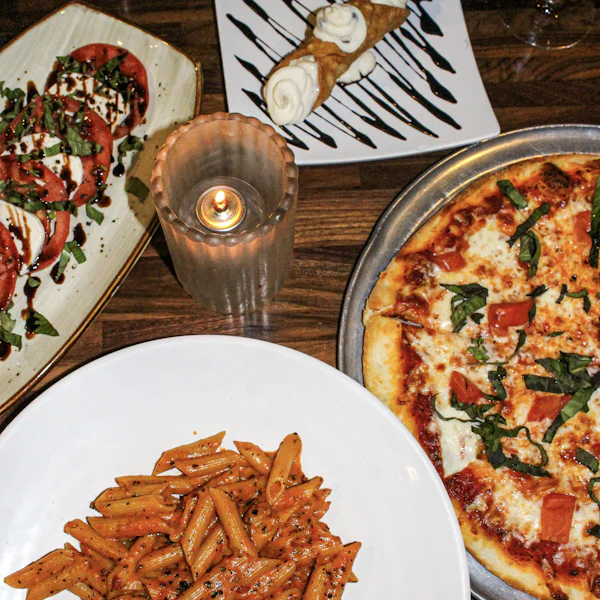 Pizza, pâtes et salades sur une table éclairée par une bougie